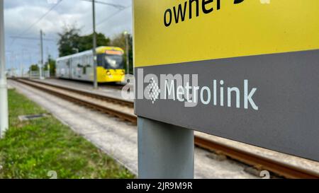 Une vue du logo Manchester Metrolnk avec un tramway de M5000 au départ de la station Martinscroft dans le fond du bckground Banque D'Images