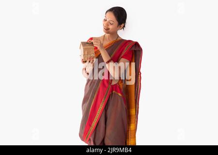 Portrait d'une femme Maharashtrian mettant la pièce dans la boîte à monnaie Banque D'Images