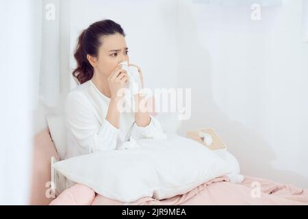 Portrait d'une jeune femme éternuant dans un tissu Banque D'Images