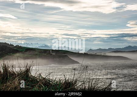 Paysage de la côte de la mer Cantabrique dans la ville de Comillas en Cantabrie (Espagne), avec les sommets enneigés de l'Europe en arrière-plan Banque D'Images