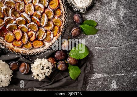 Tarte maison avec prunes sur la table sur fond de pierre blanche Banque D'Images