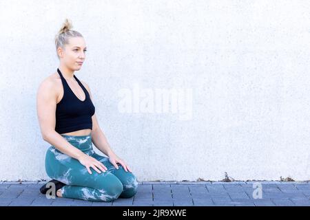 Jeune femme sportive blanche blonde vêtue de vêtements de sport noirs et bleus utilise un téléphone portable dans le centre de fitness. Femme jouant au jeu sur smartphone dans la salle de gym. Fille sportive réseautage social avec smartphone dans le club de santé après l'entraînement. Photo de haute qualité Banque D'Images