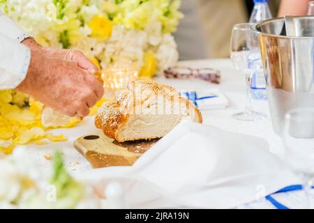 La tradition de couper et de prendre un morceau de pain Challah lors d'une réception de mariage Banque D'Images