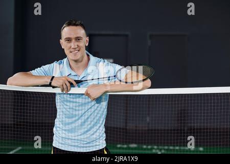 Joueur de badminton professionnel souriant debout sur le filet avec raquette à la main Banque D'Images