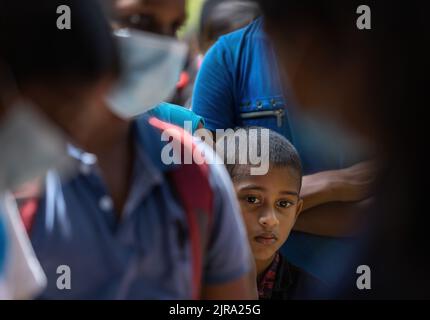 Enfant en attente de recevoir un colis alimentaire d'une communauté almsdonnant ardemment pieping: Galle, Sri Lanka 30th juillet 2022 Banque D'Images