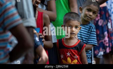 Enfant en attente de recevoir un colis de nourriture d'une communauté almsdonning ardemment peeking: Galle, Sri Lanka 30th juillet 2022 Banque D'Images