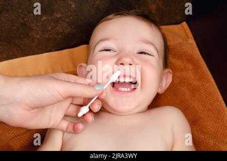 Une mère nettoie son nez avec un coton-tige à un bébé garçon heureux. Maman nettoie les narines d'un enfant souriant. Enfant d'un an Banque D'Images