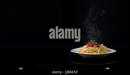 Cuire à la vapeur de délicieux spaghetti bolognaise sur fond noir. Espace de texte vide Banque D'Images