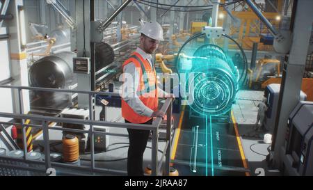 Un ingénieur sur une ligne robotique de haute technologie pour la production de moteurs aérospatiaux contrôle l'information à l'aide d'une interface graphique innovante et moderne. Banque D'Images