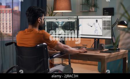 Vue arrière d'un développeur masculin méconnaissable avec un handicap assis sur un fauteuil roulant et rendant le modèle 3D de robot sur un ordinateur pendant le travail dans un salon sombre à la maison Banque D'Images