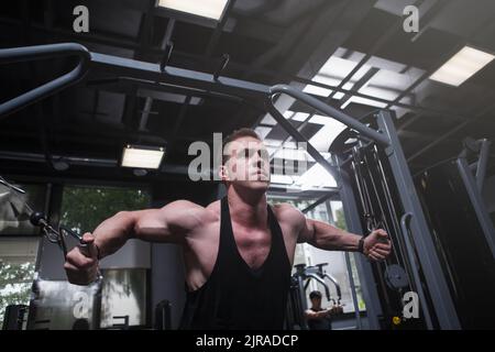 Photo sous angle d'un carrossier travaillant sur une machine de gym à câble croisé Banque D'Images