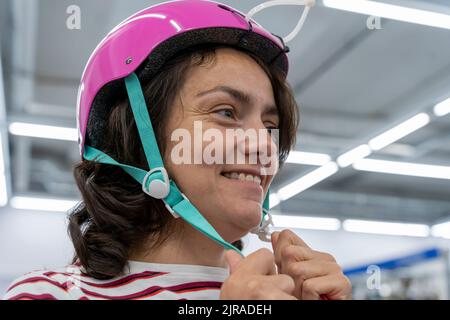 une femme essaie un casque de vélo dans un magasin d'articles de sport Banque D'Images