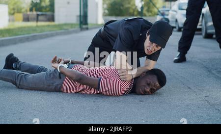 Un policier afro-américain discutant avec un condamné noir près d'une collègue féminine au pistolet lors d'une arrestation derrière la grille Banque D'Images