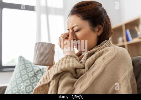 femme asiatique malade qui boit du thé chaud à la maison Banque D'Images