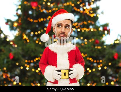 triste homme en costume du père noël sur l'arbre de noël Banque D'Images