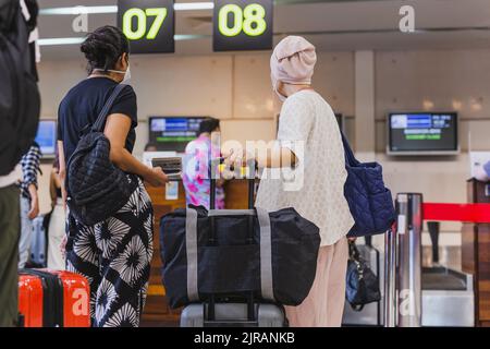 Deux femmes passagers avec masque s'enregistrer à l'aéroport. Banque D'Images