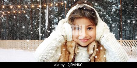 fille en casque antibruit à la patinoire en hiver Banque D'Images