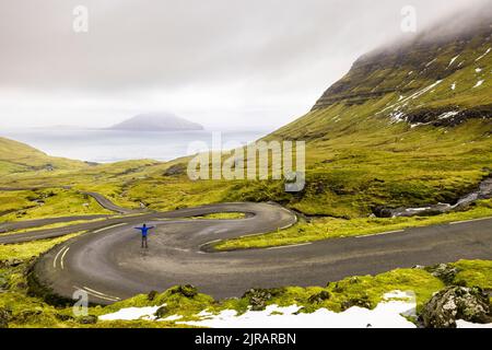 Îles Féroé, Streymoy, homme debout au milieu d'une route sinueuse éloignée Banque D'Images