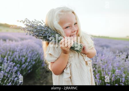 Fille souriante avec bouquet de lavande debout dans le champ Banque D'Images