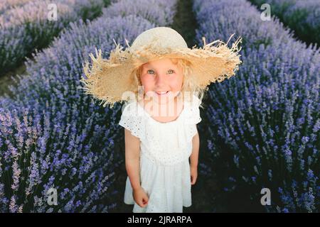 Jolie fille souriante portant un chapeau de paille debout dans le champ de lavande Banque D'Images