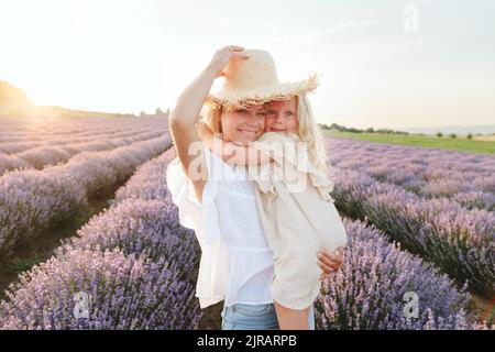 Jolie fille avec une mère portant un chapeau debout dans un champ de lavande Banque D'Images