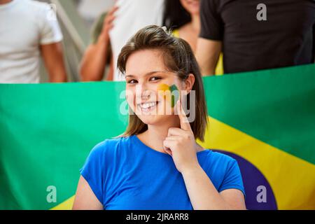 Femme souriante montrant le drapeau du Brésil peint sur le visage Banque D'Images