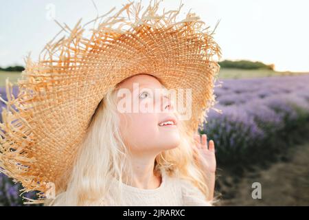 Jolie fille souriante portant un chapeau debout dans un champ de lavande Banque D'Images