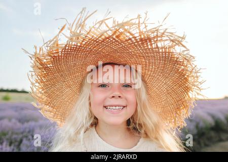 Bonne fille portant un chapeau de paille debout dans le champ de lavande Banque D'Images