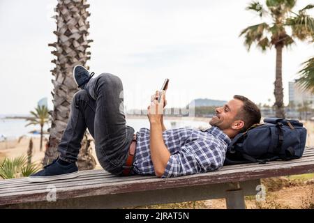 Souriant homme mûr se détendant à l'aide d'un smartphone sur la paillasse Banque D'Images