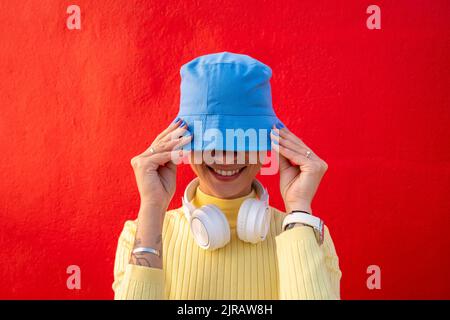 Femme souriante avec un casque couvrant le visage avec un chapeau bleu Banque D'Images