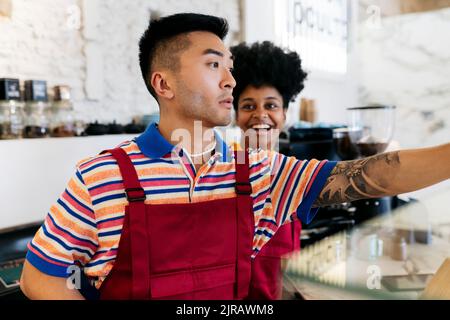 Un jeune homme heureux regardant un collègue qui travaille dans un café Banque D'Images