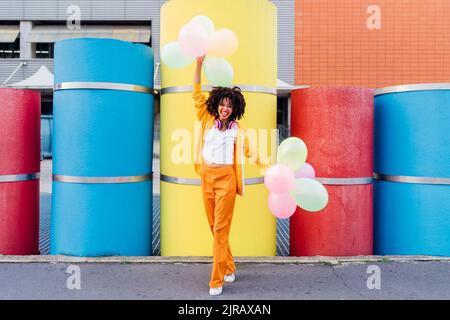 Bonne femme jouant avec des ballons colorés devant des tuyaux Banque D'Images