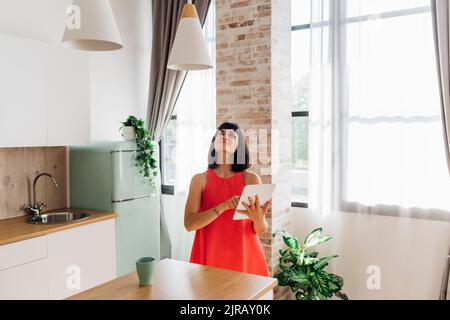 Femme utilisant l'automatisation à la maison dans la cuisine à la maison Banque D'Images