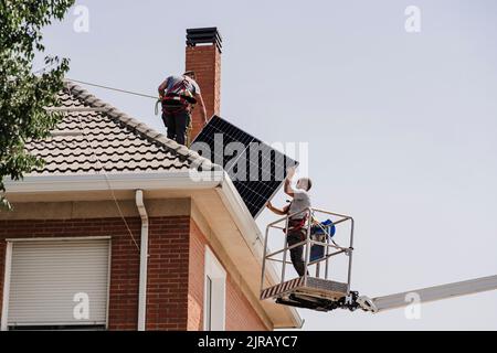 Techniciens installant des panneaux solaires sur le toit Banque D'Images