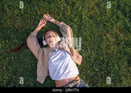 Femme souriante couchée et écoutant de la musique au parc Banque D'Images