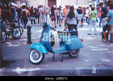 Un Vespa italien bleu garé dans une rue bondée en Espagne Banque D'Images