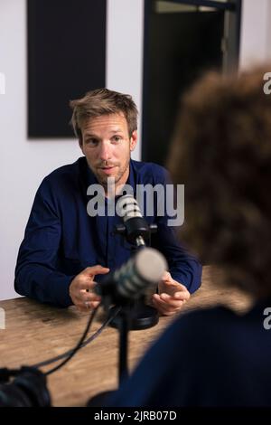 Homme parlant avec un invité dans un studio d'enregistrement Banque D'Images