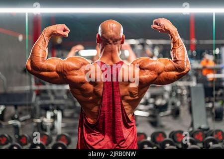 Bodybuilder flexion musculaire dos debout dans la salle de gym Banque D'Images