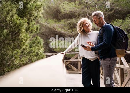 Une femme heureuse avec un homme qui utilise un smartphone à la passerelle Banque D'Images