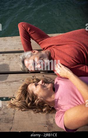 Femme mûre et gaie avec un homme allongé sur le plancher Banque D'Images