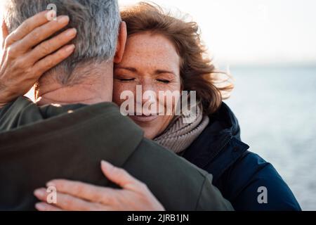 Femme mûre souriante embrassant l'homme en vacances Banque D'Images
