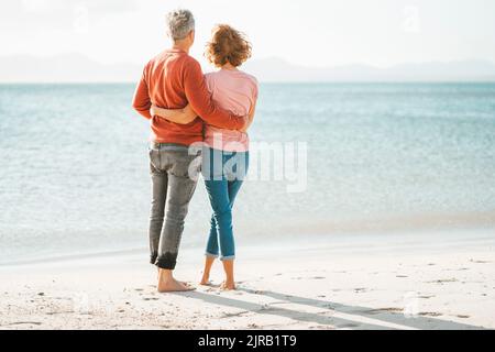 Couple d'âge mûr affectueux avec des bras autour l'un de l'autre debout sur la rive à la plage Banque D'Images