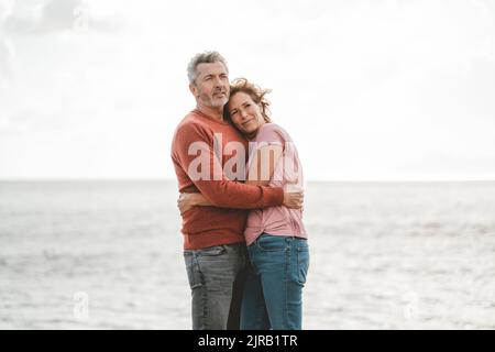 Couple d'âge mûr aimant s'embrassant les uns les autres à la plage en vacances Banque D'Images