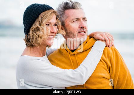 Femme heureuse avec le bras autour de l'homme à la plage Banque D'Images