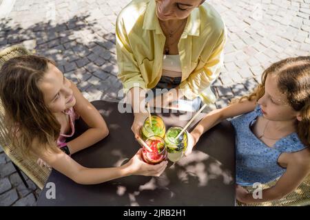 Une mère et des filles souriantes qui toaster des cocktails avec de la paille de canne Banque D'Images