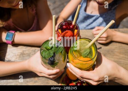 Mains de la mère et des filles toaster des cocktails avec de la paille de canne Banque D'Images