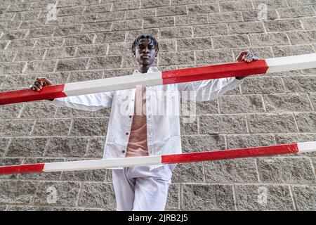 Jeune homme avec des dreadlocks debout près de la main courante Banque D'Images