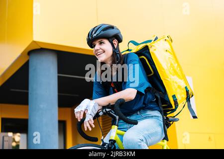 Bonne femme de livraison avec sac à dos assis sur un vélo Banque D'Images