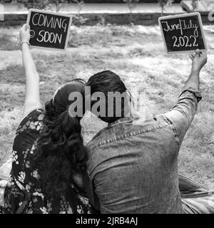 Couple indien posant pour une pousse de bébé de maternité. Le couple pose dans une pelouse avec de l'herbe verte et la femme est fautante de sa bosse de bébé à Lodhi Garde Banque D'Images