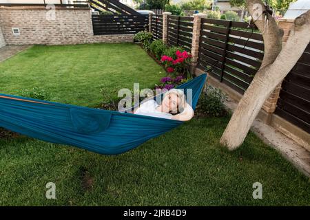 Femme d'âge mûr se détendant sur un hamac dans le jardin Banque D'Images